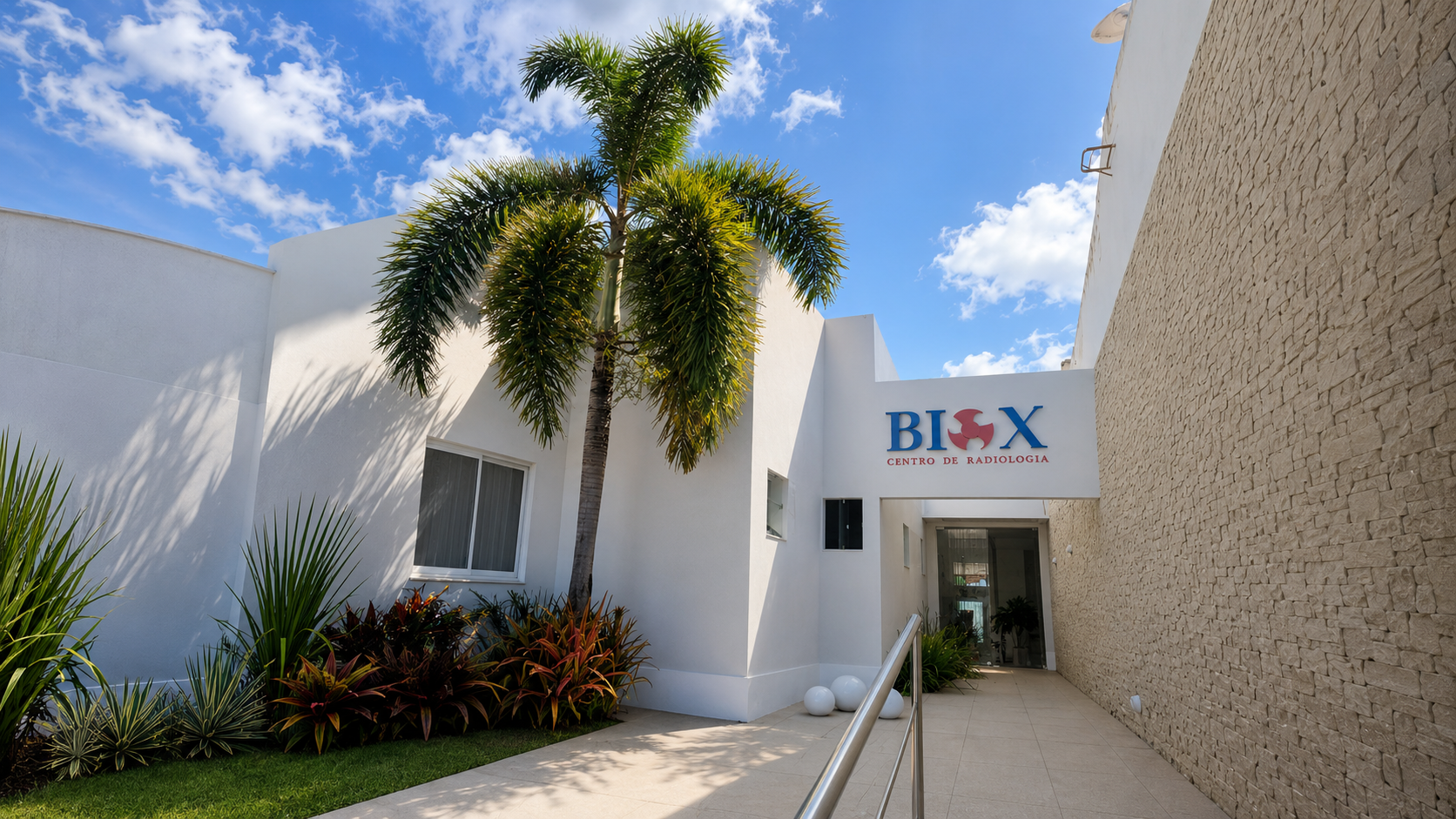 Entrada da BioX Centro de Radiologia com fachada clara e jardim